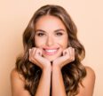 Woman smiling and posing with her hands tucked under her chin