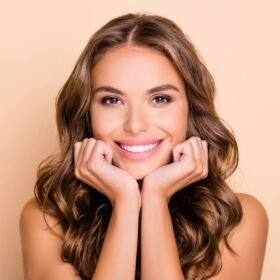 Woman smiling and posing with her hands tucked under her chin