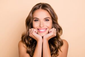 Woman smiling and posing with her hands tucked under her chin